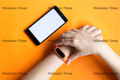Fitness,Tracker,On,A,Woman,Hand,On,An,Orange,Background