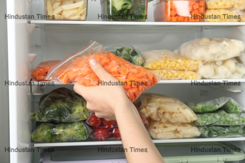 Woman,Putting,Plastic,Bag,With,Carrot,In,Refrigerator,With,Frozen
