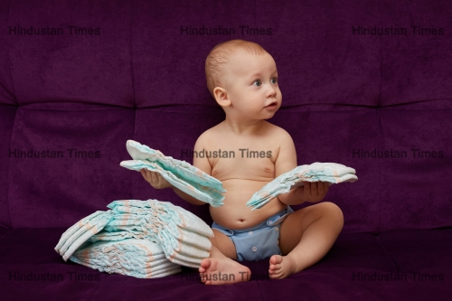 Little,Boy,With,Stack,Of,Diapers,Or,Nappies,On,Purple