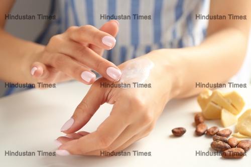 Woman,Applying,Cocoa,Butter,Lotion,Onto,Hand,Over,Table