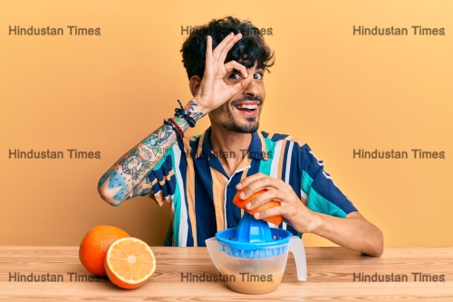 Young,Hispanic,Man,Sitting,On,The,Table,Using,Juicer,Smiling