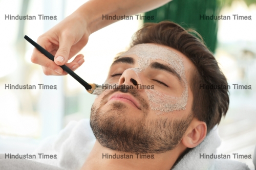 Beautician,Applying,Scrub,Onto,Young,Man's,Face,In,Spa,Salon