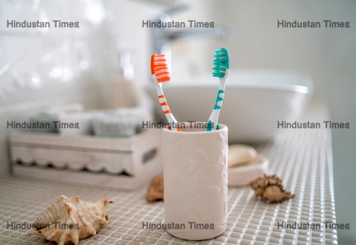 Two,Colorful,Toothbrushes,Stand,In,A,Ceramic,Glass,Against,The