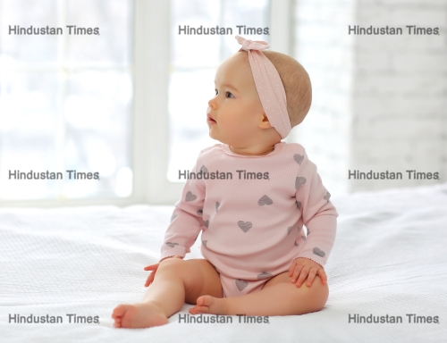Cute,8-month-old,Baby,With,A,Headband,On,A,White,Bed