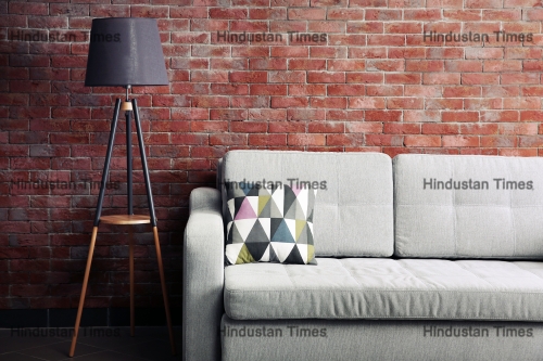 Grey,Sofa,And,Floor,Lamp,Against,Brick,Wall,In,The