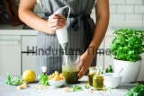 Woman,Using,Hand,Blender,To,Make,Pesto.,White,Kitchen,Interior