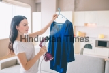 Woman,Is,Steaming,Blue,Shirt,In,Room.,She,Holds,Small