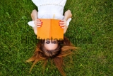 A,Young,Girl,Reading,A,Book,Lying,On,A,Green