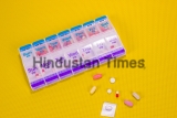 Weekly,Pill,Box,Container,On,Patterned,Yellow,Background