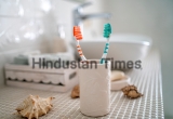 Two,Colorful,Toothbrushes,Stand,In,A,Ceramic,Glass,Against,The