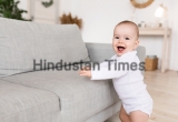 Cute,Little,Baby,Girl,Smiling,To,Camera,Standing,Near,Sofa